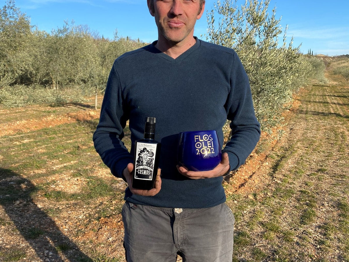 Olive grower of La Magnanerie in the estate's Ardèche groves, holding a bottle and a tin of olive oil