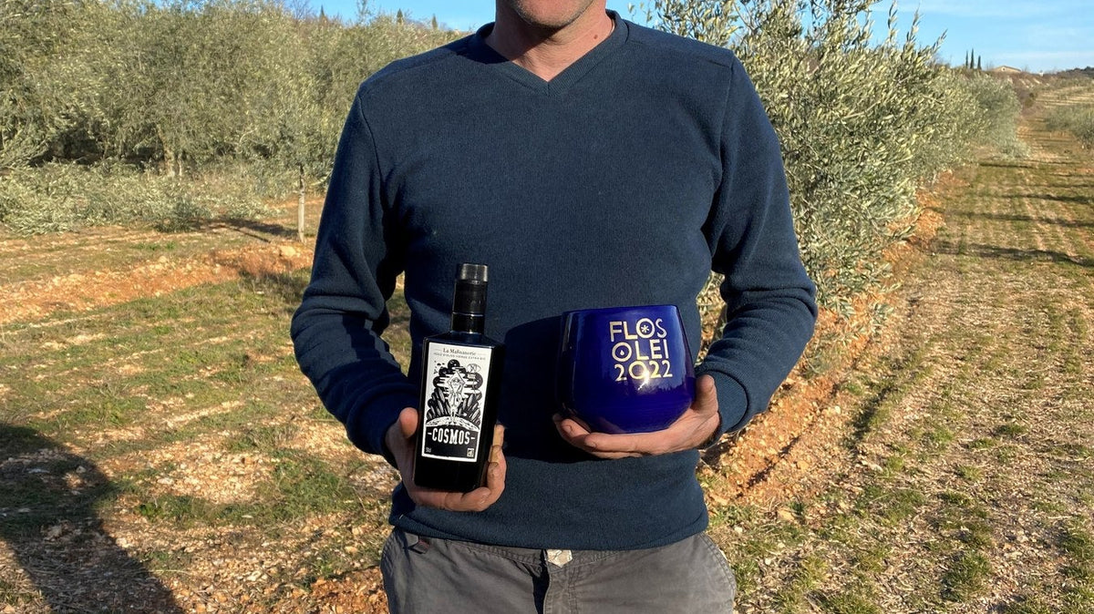 Olive grower of La Magnanerie in the estate's Ardèche groves, holding a bottle and a tin of olive oil