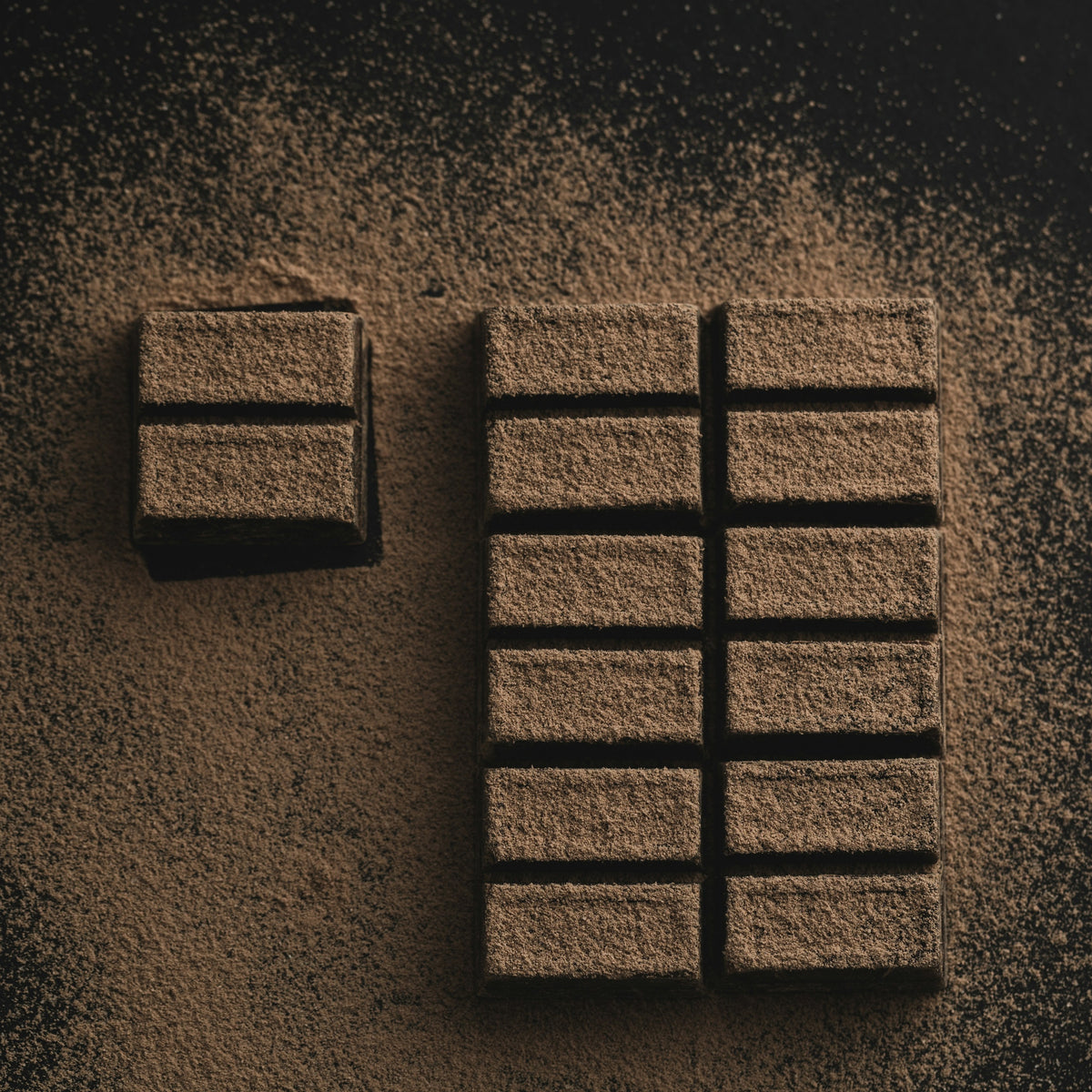 Dark chocolate bar dusted with cocoa powder on a dark background