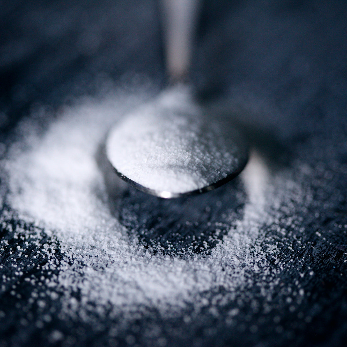 Spoon resting in scattered white sugar
