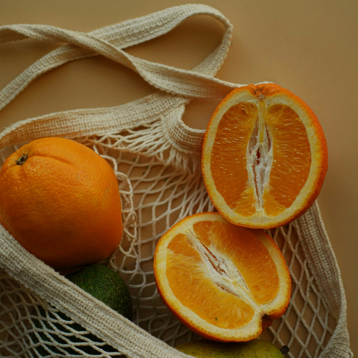 Cotton net shopping bag with oranges and an avocado