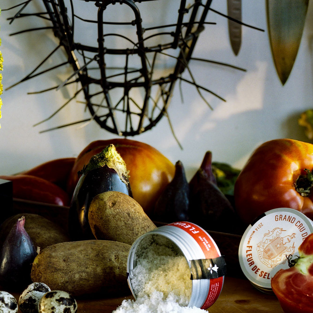 Binet 1660 fleur de sel spilling from its tin beside fresh vegetables