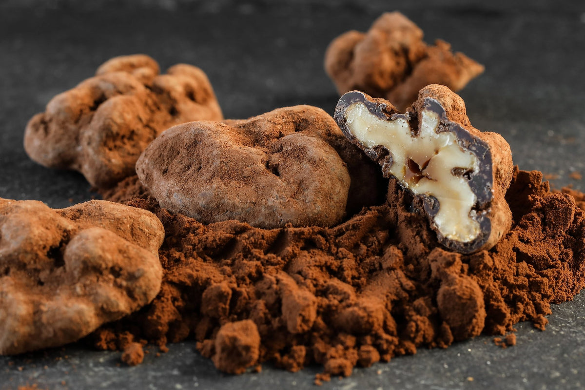 Noix enrobée de chocolat du Domaine de Béquignol coupée en deux sur un lit de cacao en poudre