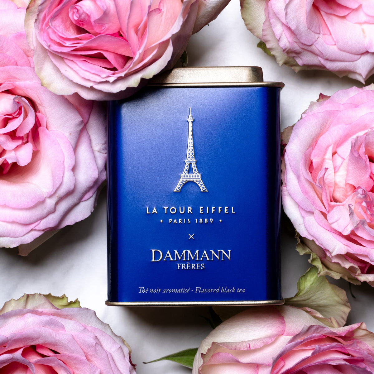 Boîte Thé Tour Eiffel de Dammann Frères parmi des roses