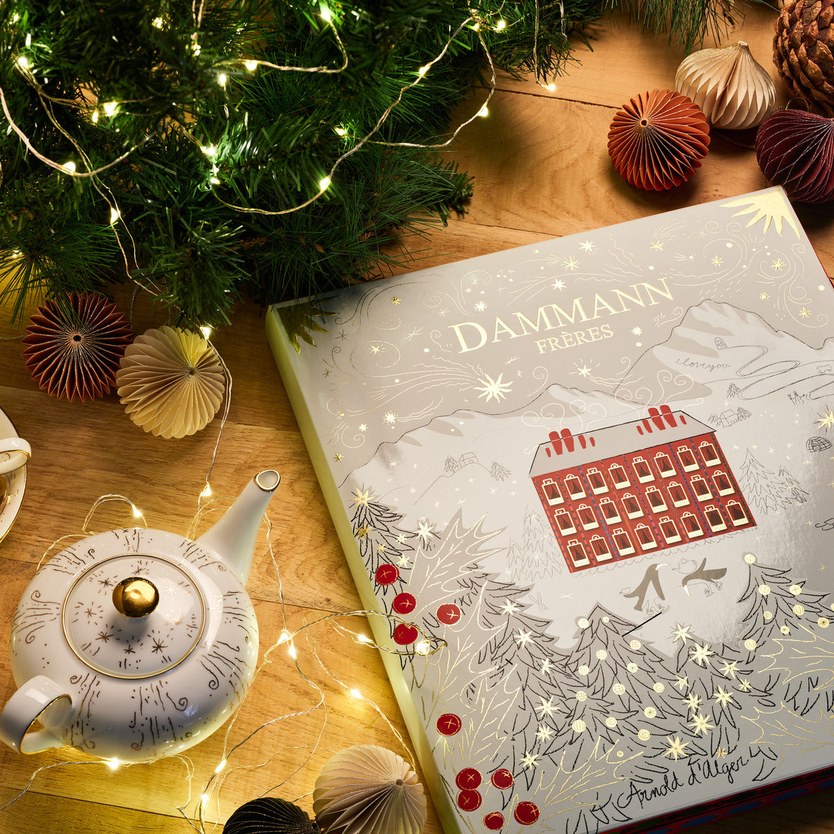 Advent Calendar by Dammann Frères on a wooden table with a teapot, a cup of tea and Christmas decorations