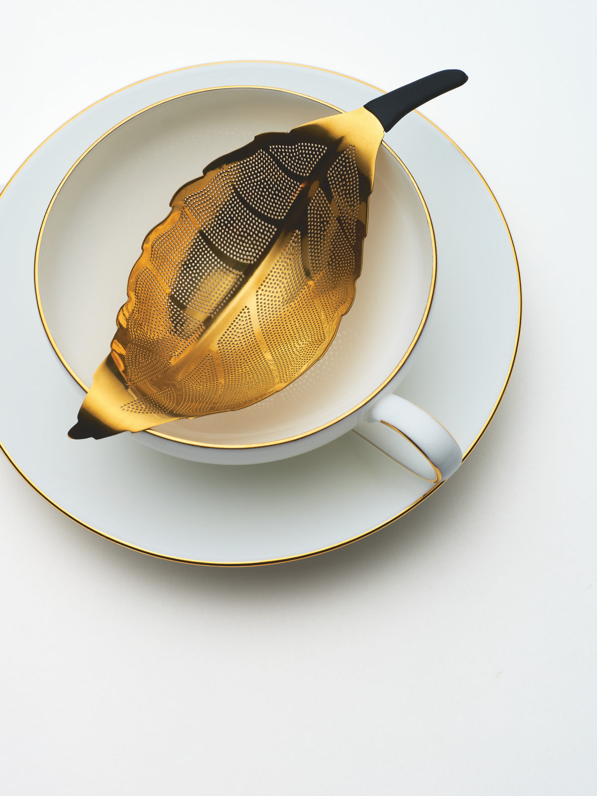 Gold Leaf Infuser by Dammann Frères resting on a porcelain cup