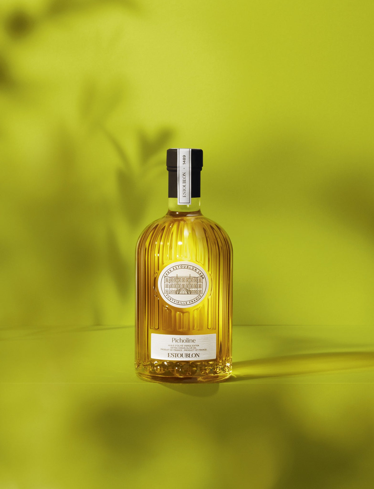 Picholine single-variety olive oil by Château d'Estoublon, styled on a lime background