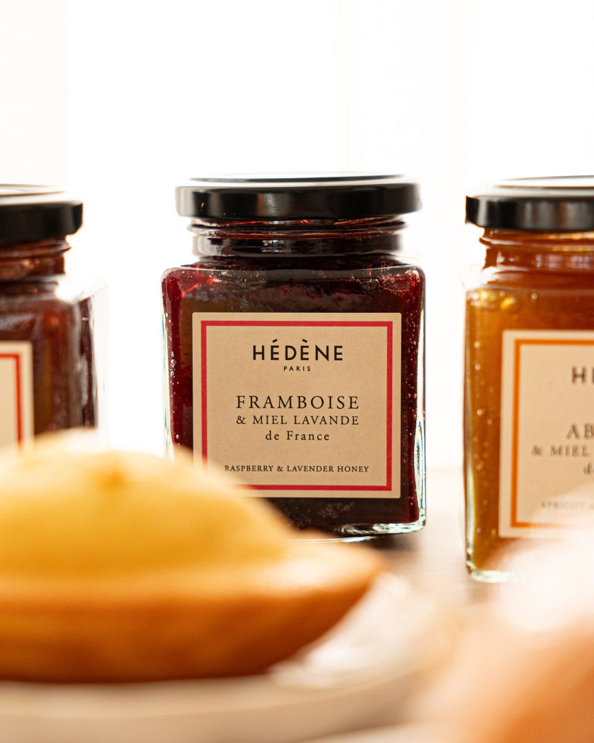 Hédène raspberry and lavender honey jam jar beside a madeleine