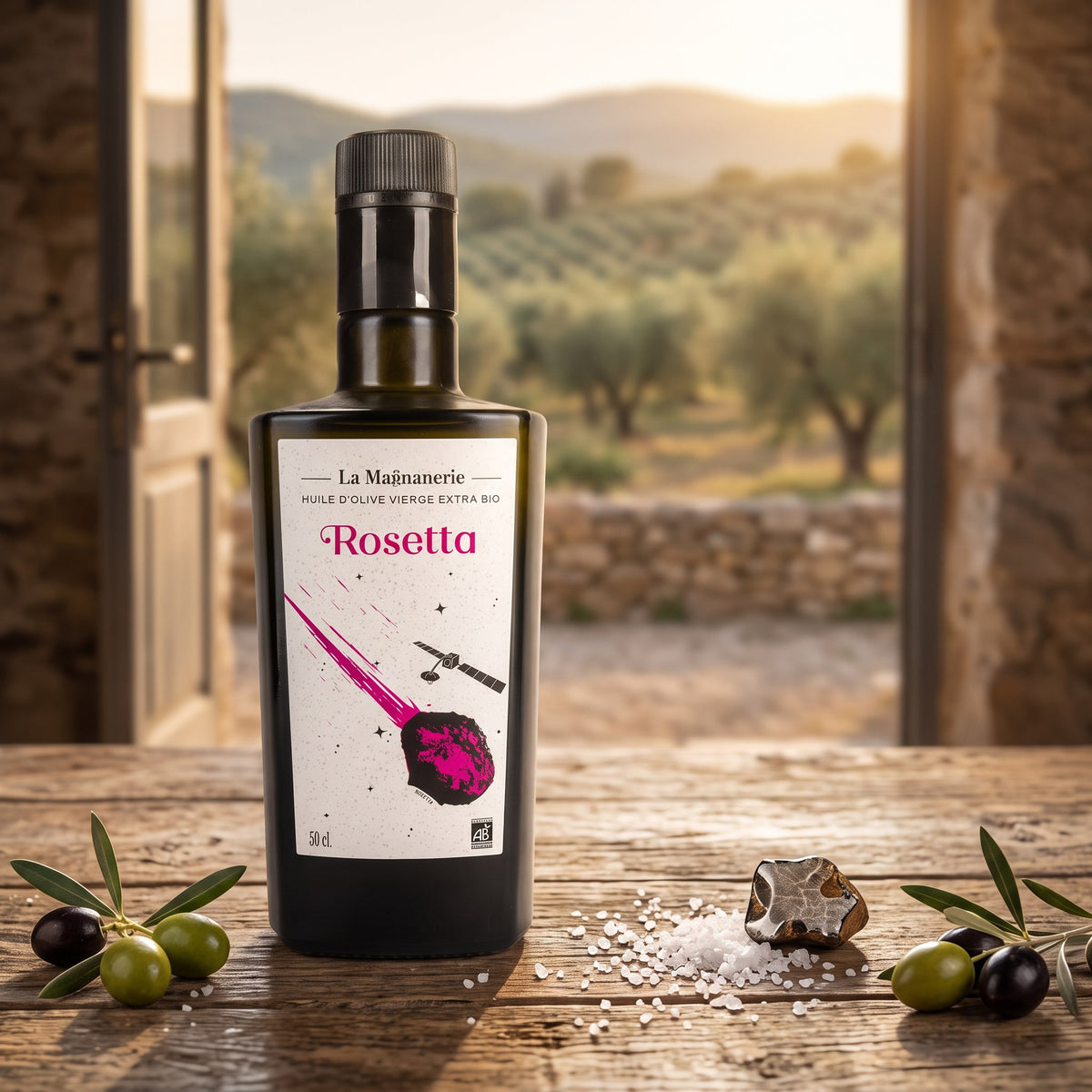 Huile d’olive biologique Rosetta de La Magnanerie sur une table en bois avec des olives et du sel marin