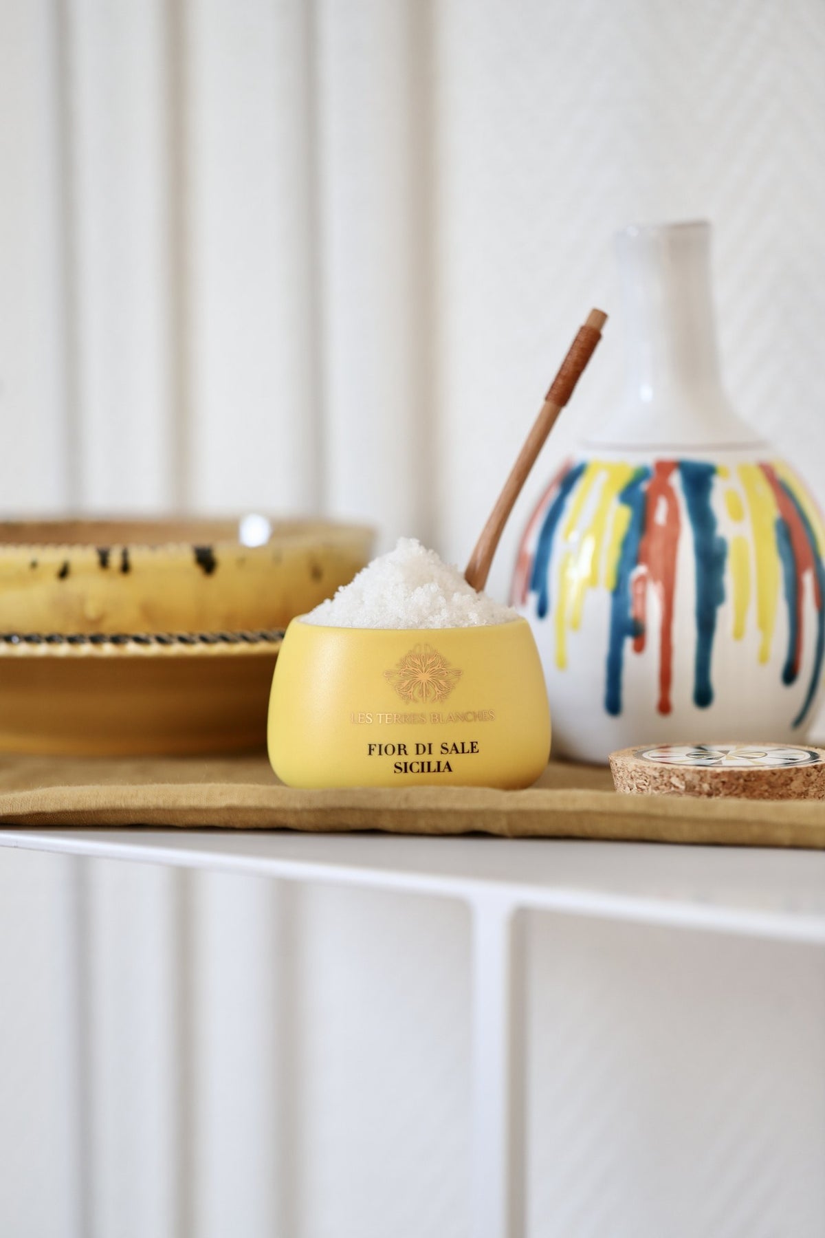 Les Terres Blanches Fior di Sale Sicilia in its yellow jar with a wooden spoon