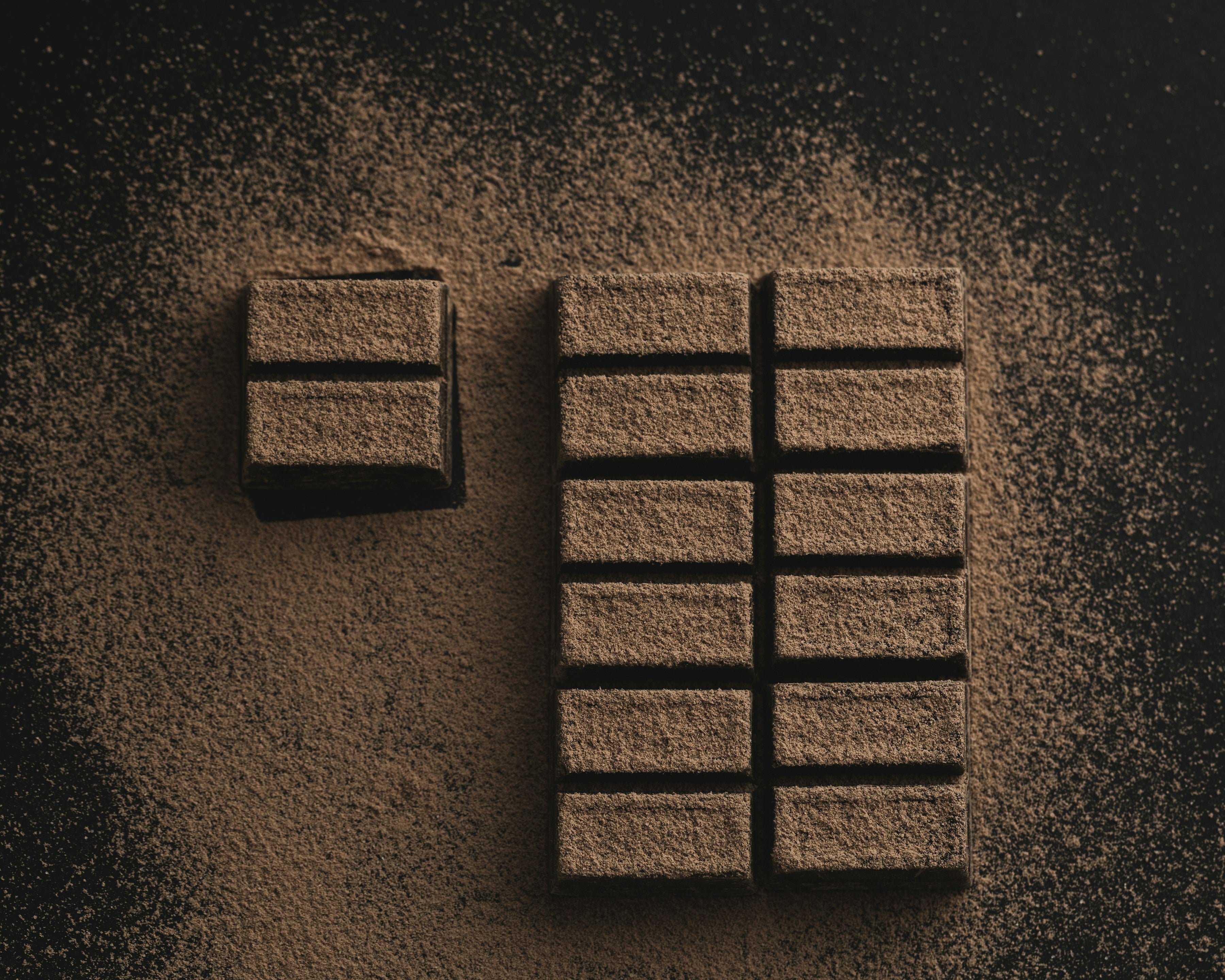 Dark chocolate bar dusted with cocoa powder on a dark background