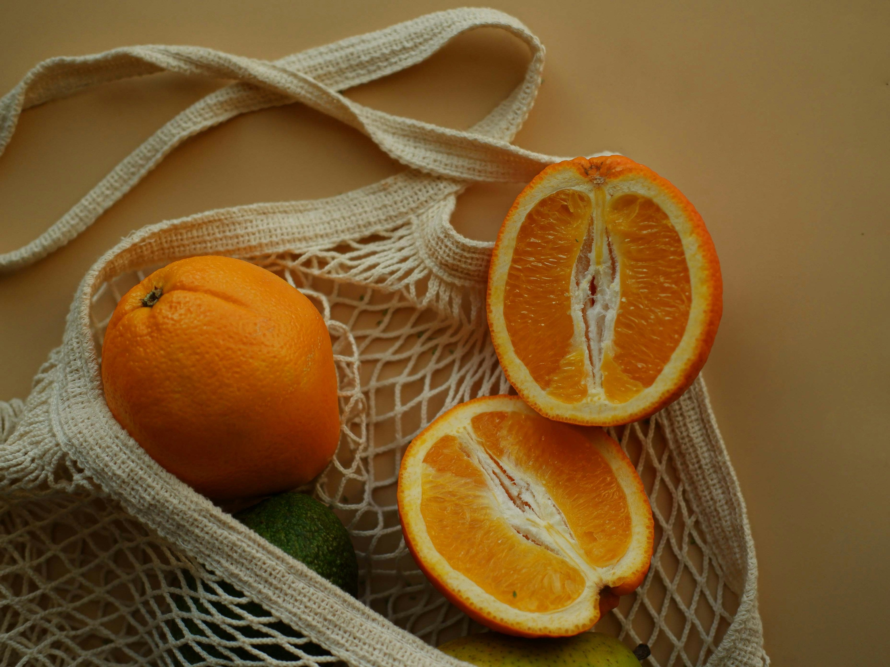 Cotton net shopping bag with oranges and an avocado