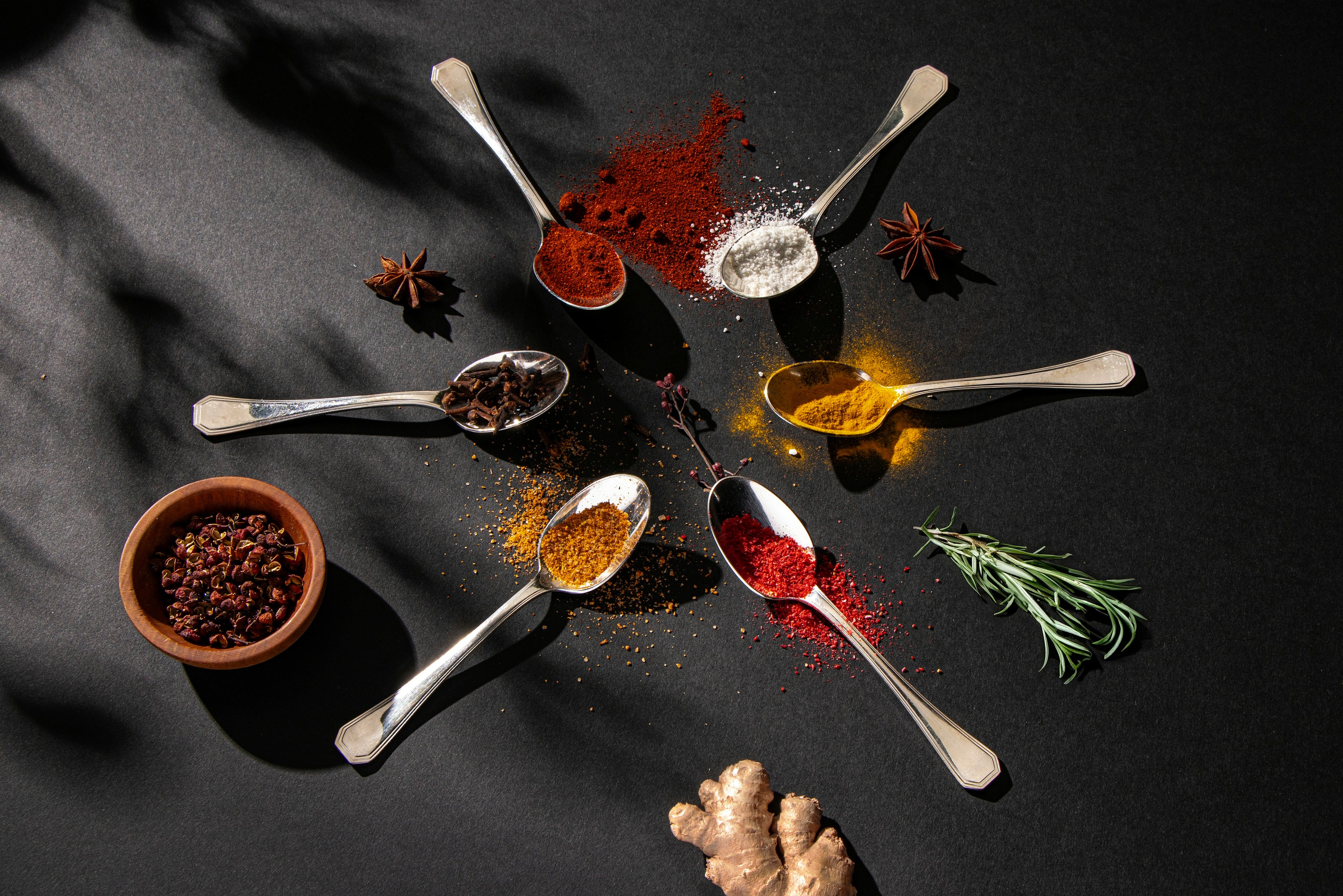 Spoons of colorful ground spices with star anise and ginger