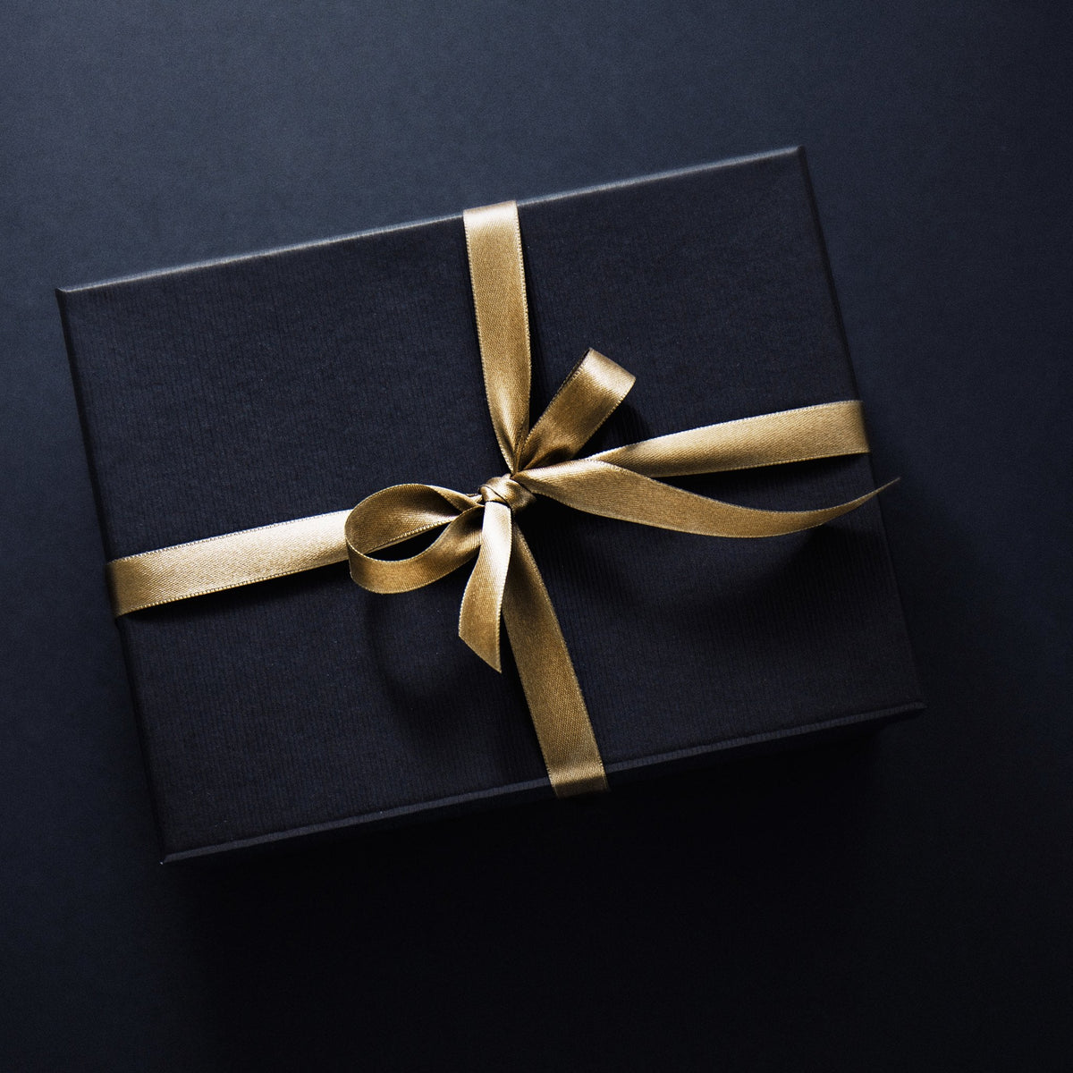 Black gift box tied with a gold satin ribbon