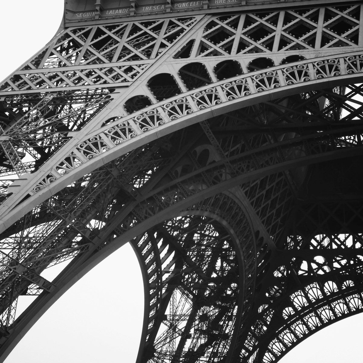 Vue en noir et blanc du treillis de fer de la tour Eiffel, en contre-plongée