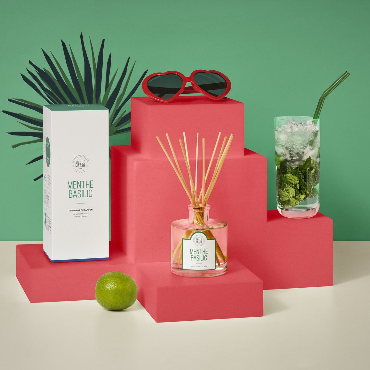 Diffuseur à bâtonnets Menthe Basilic de La Belle Mèche à côté d’un mojito