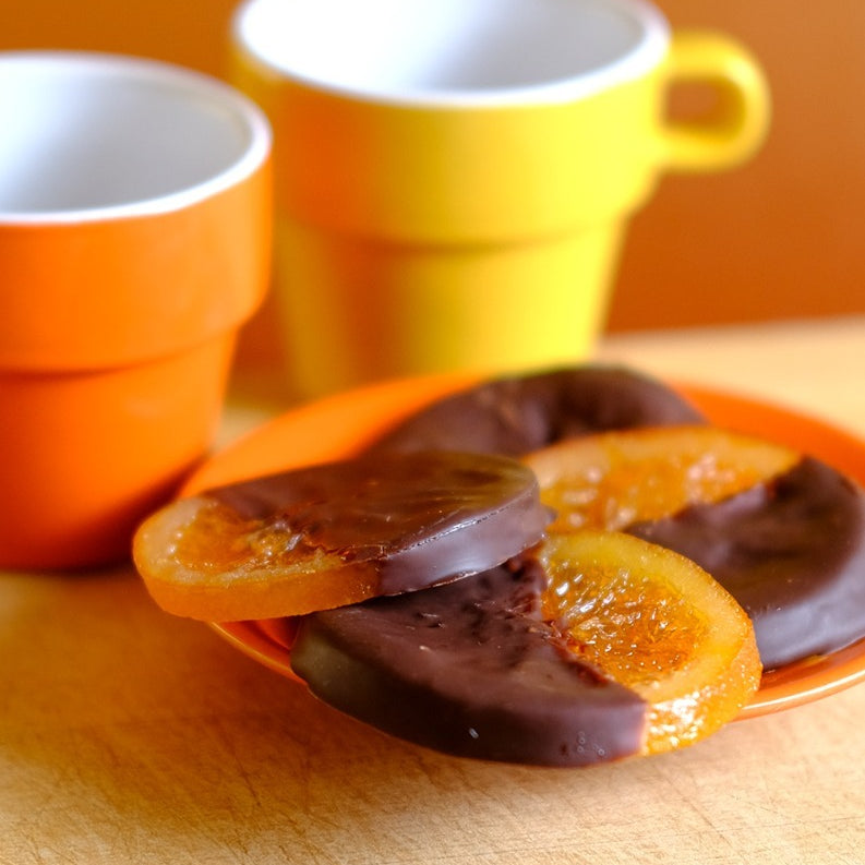 Confiserie Florian chocolate-coated candied orange slices on a plate with coffee cups
