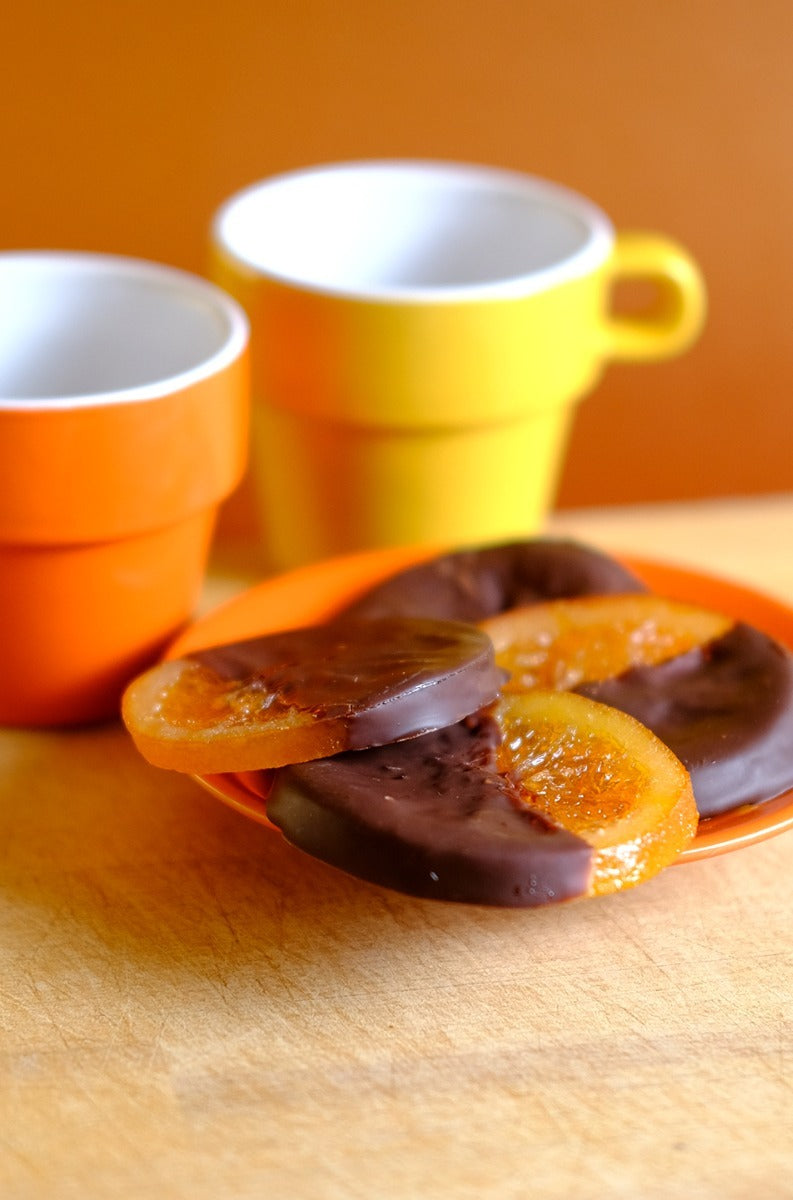 Confiserie Florian chocolate-coated candied orange slices on a plate with coffee cups