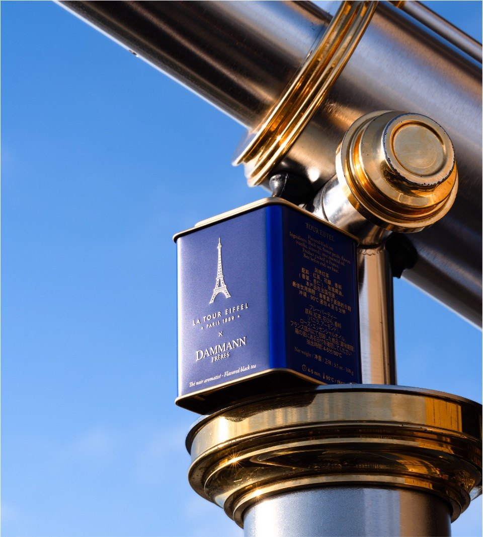 Blue Dammann Frères La Tour Eiffel tea tin on a brass telescope against a blue sky