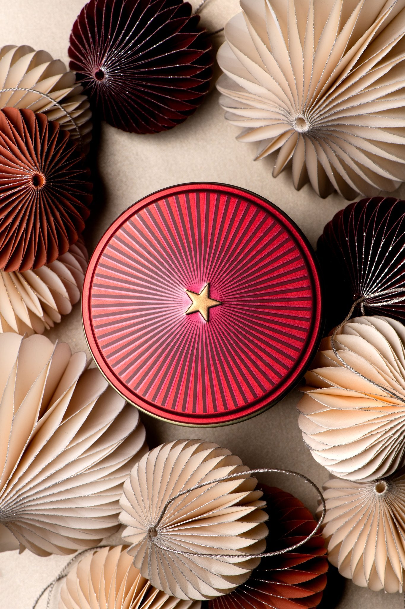 Boîte métal étoile rouge Christmas Tea de Dammann Frères parmi des boules en papier
