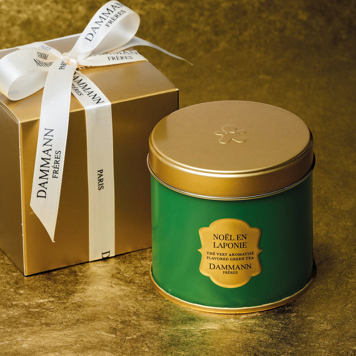 Dammann Frères Noël en Laponie green tea tin beside a gold gift box tied with a Dammann ribbon