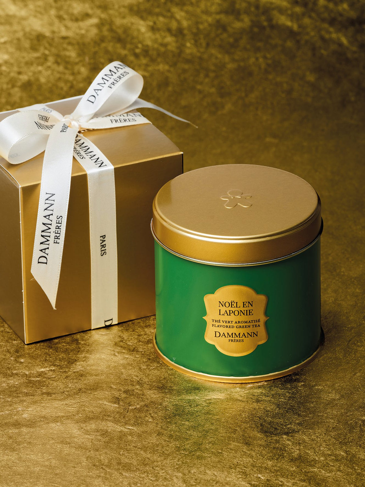Dammann Frères Noël en Laponie green tea tin beside a gold gift box tied with a Dammann ribbon