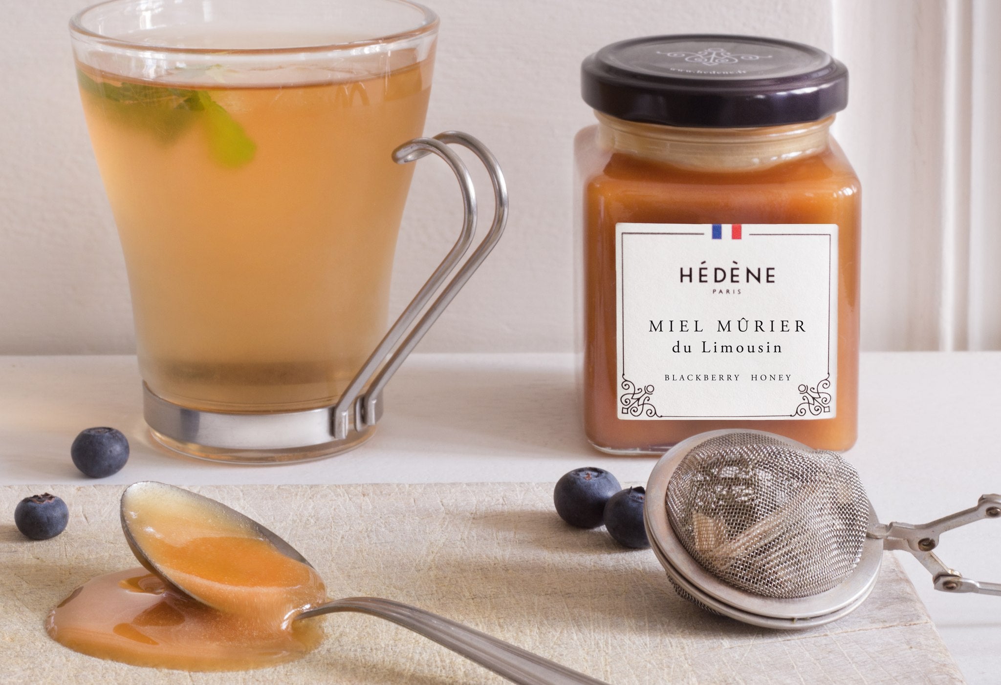 Hédène Limousin blackberry honey with a cup of herbal tea and a honey spoon