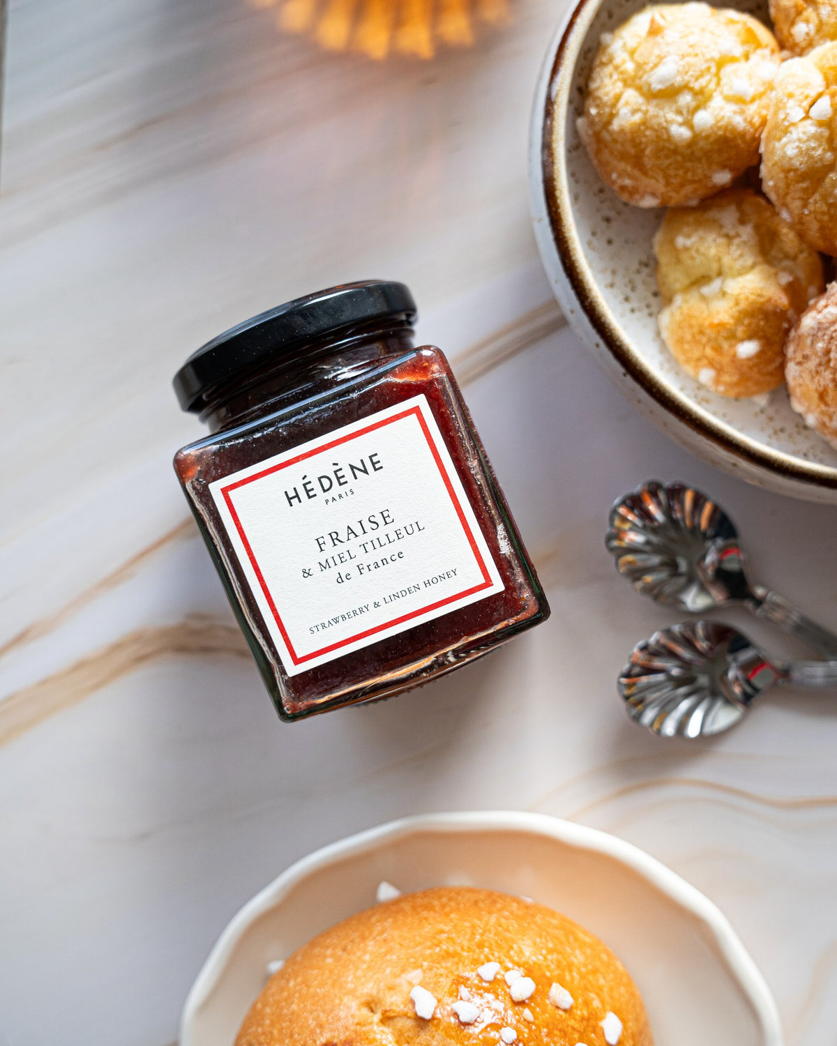 Confiture de fraises au miel de tilleul Hédène sur une table de petit-déjeuner, avec des madeleines
