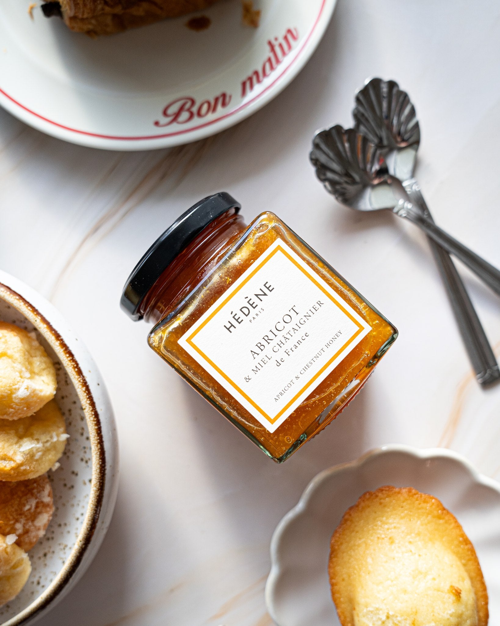 Hédène apricot jam with chestnut honey beside madeleines and teaspoons