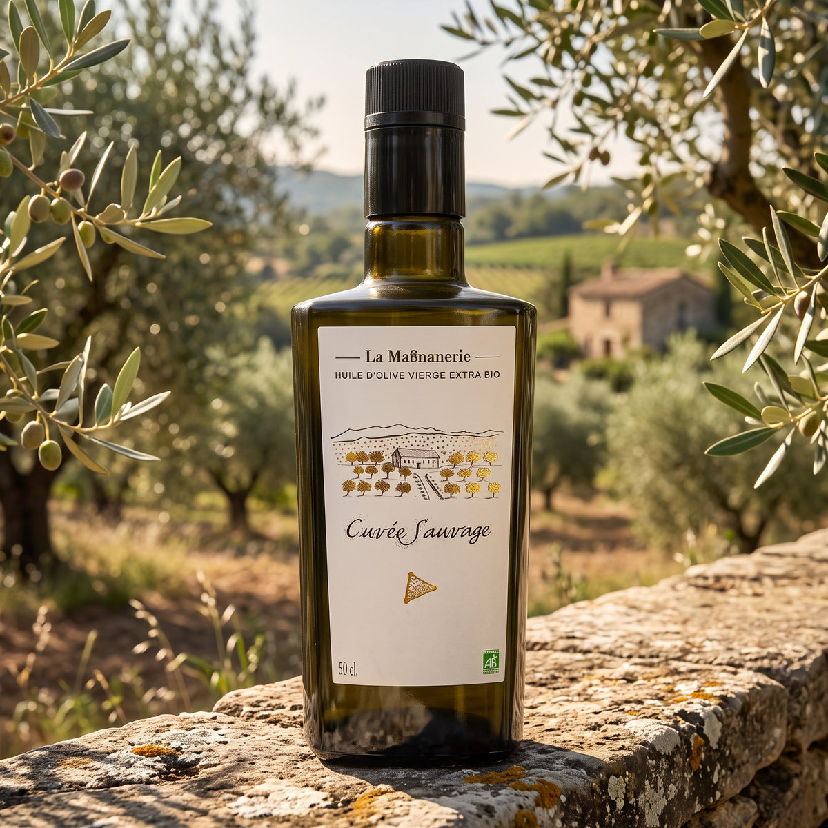 La Magnanerie Cuvée Sauvage organic olive oil on a stone wall among olive trees