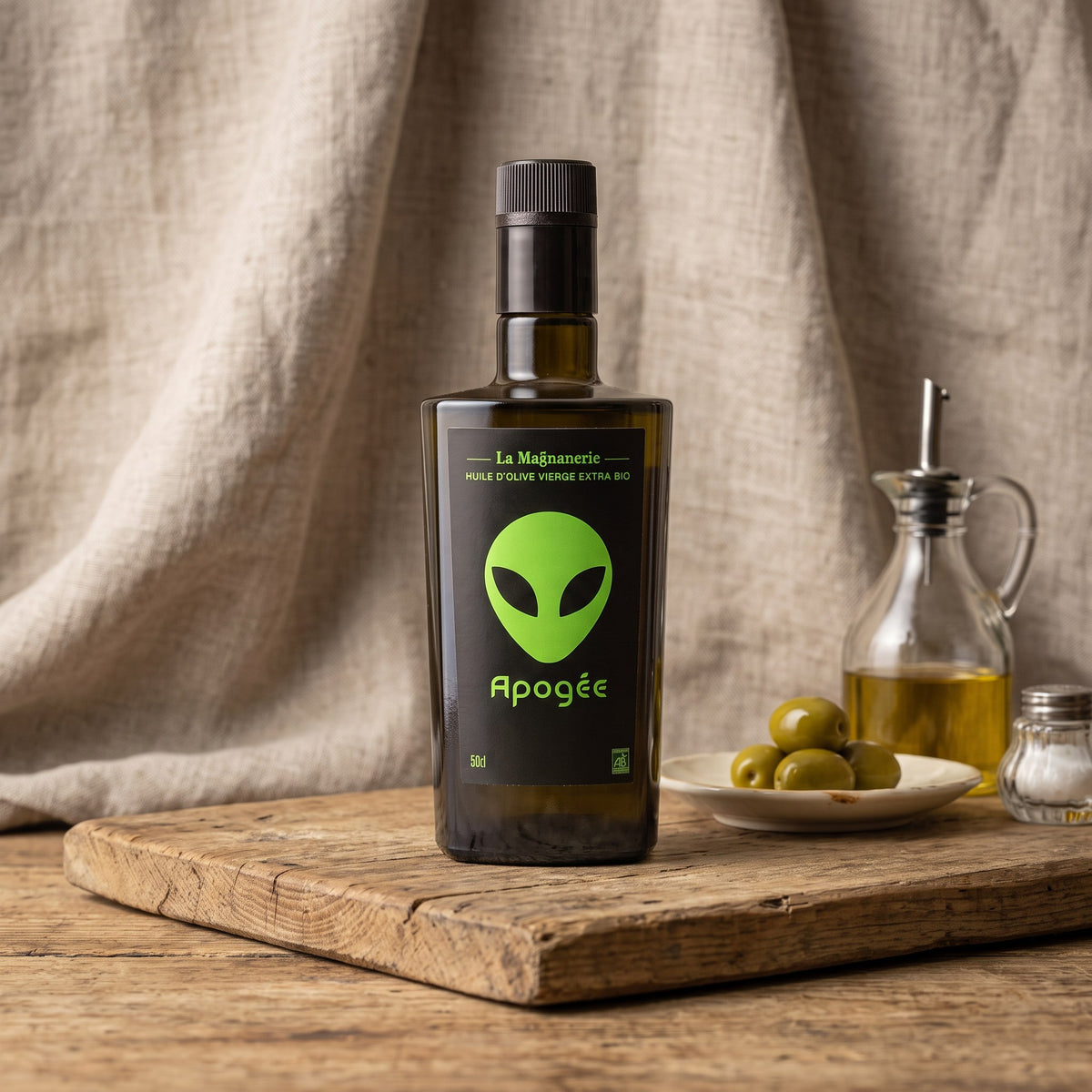 La Magnanerie Apogée organic olive oil beside a cruet and green olives