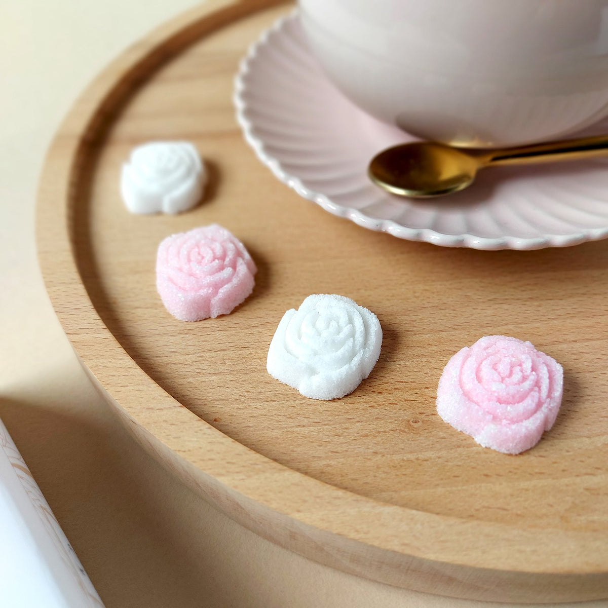Canasuc pink and white rose-shaped sugars on a wooden tray