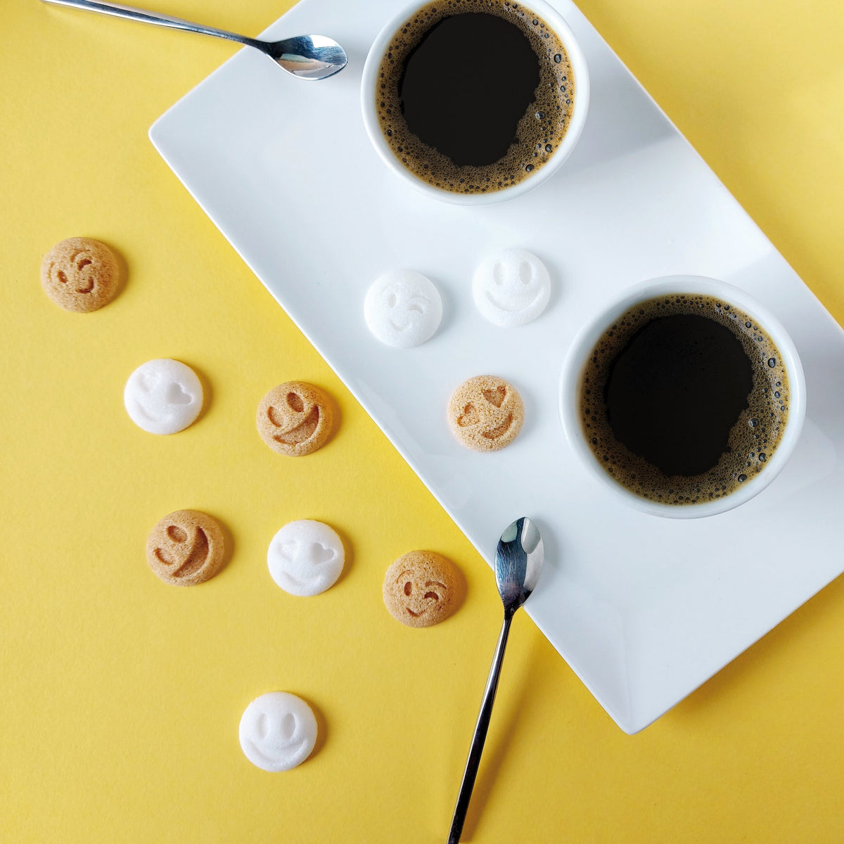 Canasuc smiley sugars with two cups of coffee on a yellow table